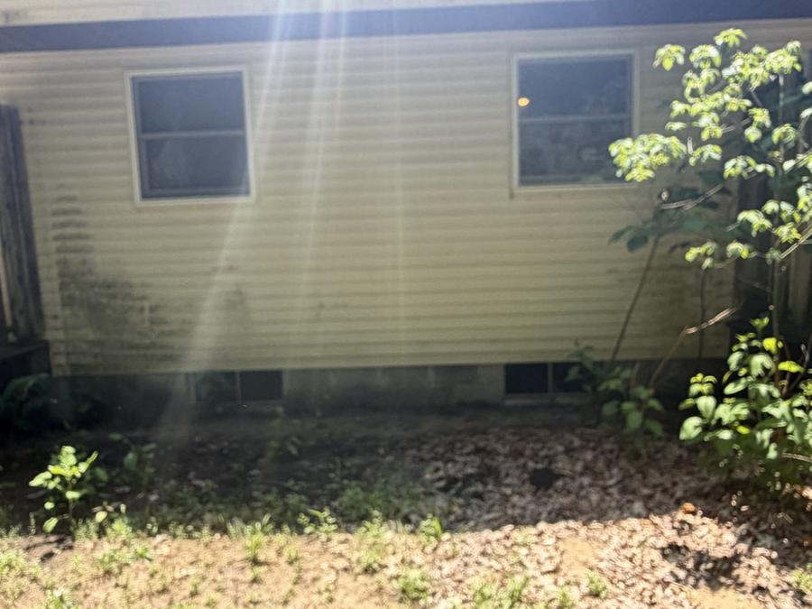 Dingy house siding wall with two windows before pressure washing